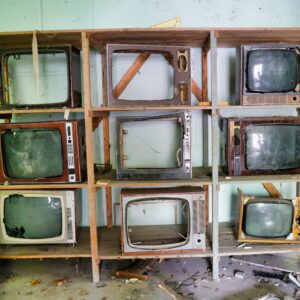 old tvs on a shelving unit with their screens smashed out