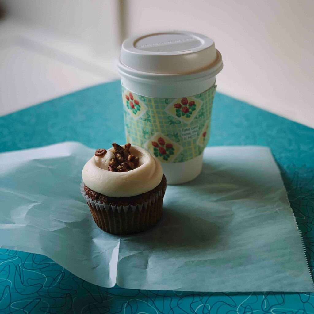 reusable coffee cup and a cupcake on a blue background