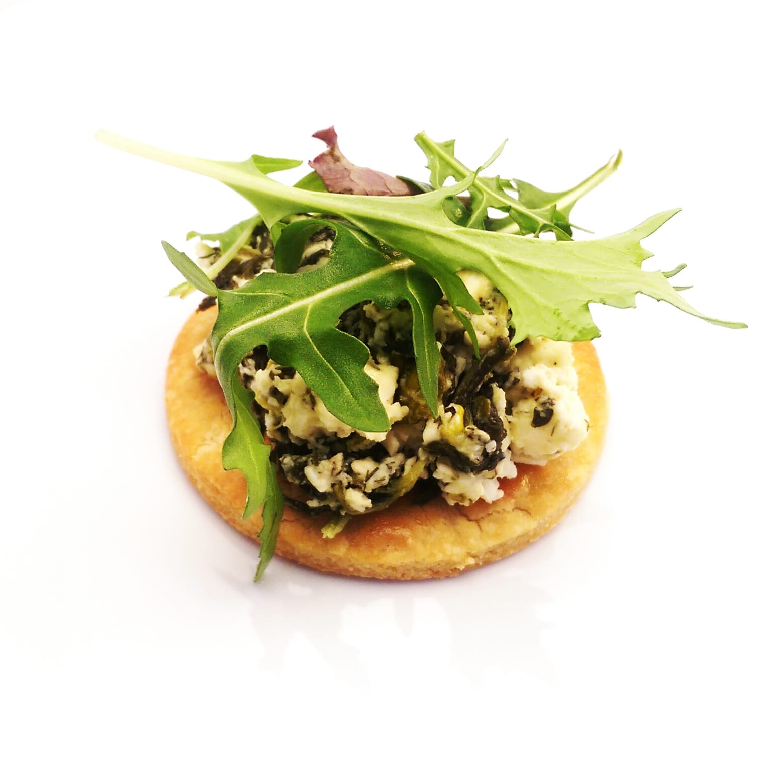pastry disk with feta and spinach filling on top covered with salad