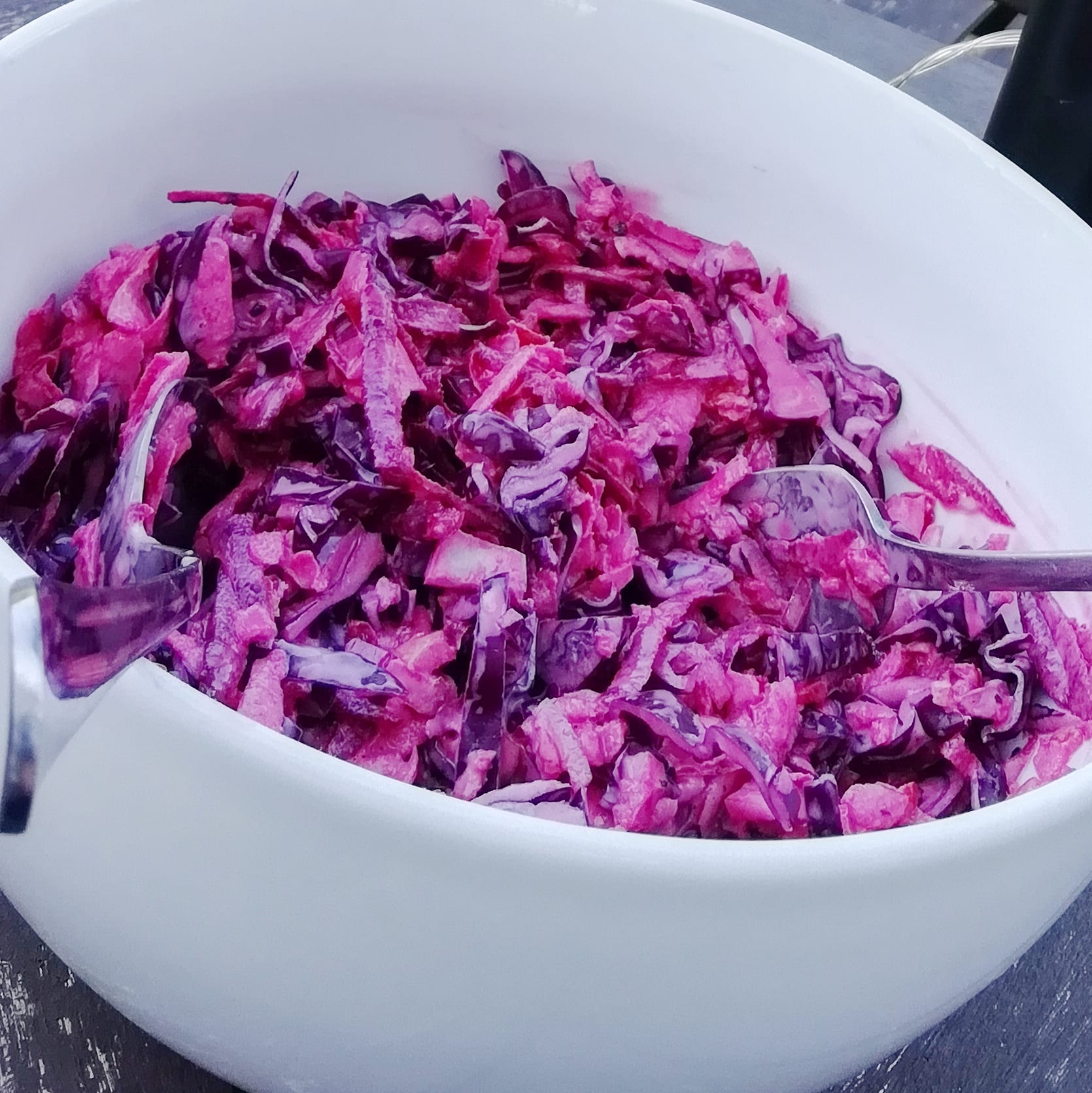 white bowl with pink coleslaw and serving implements