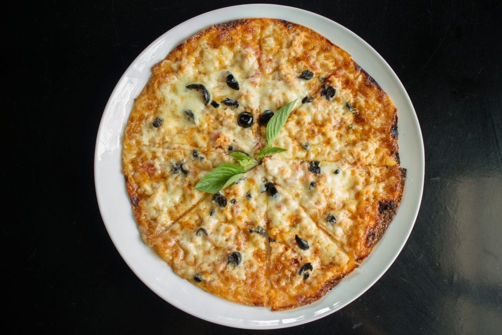 pizza on a plate with a sprig of basil
