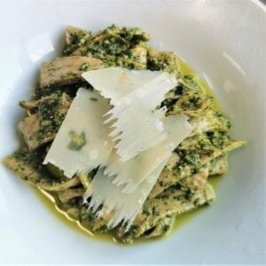 white bowl of low carb pesto pasta with shavings of parmesan in the centre