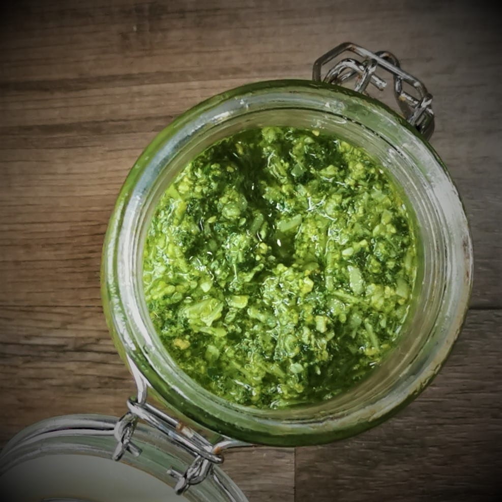 glass jar of pesto on a wood surface