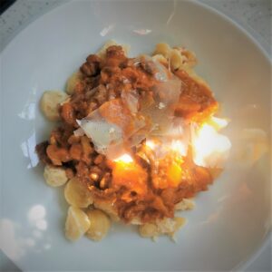 white bowl with low carb gnocchi and bolognese meat sauce topped with parmesan shavings