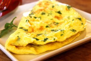 A square white plate with a folded egg omelette with herbs