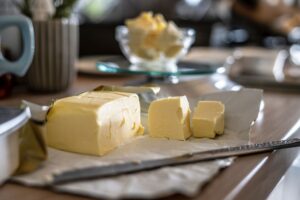 butter on a white plate cut into slices with a knife in the foreground