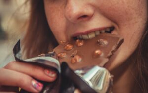 a closeup of a woman eating a bar of hazelnut chocolate
