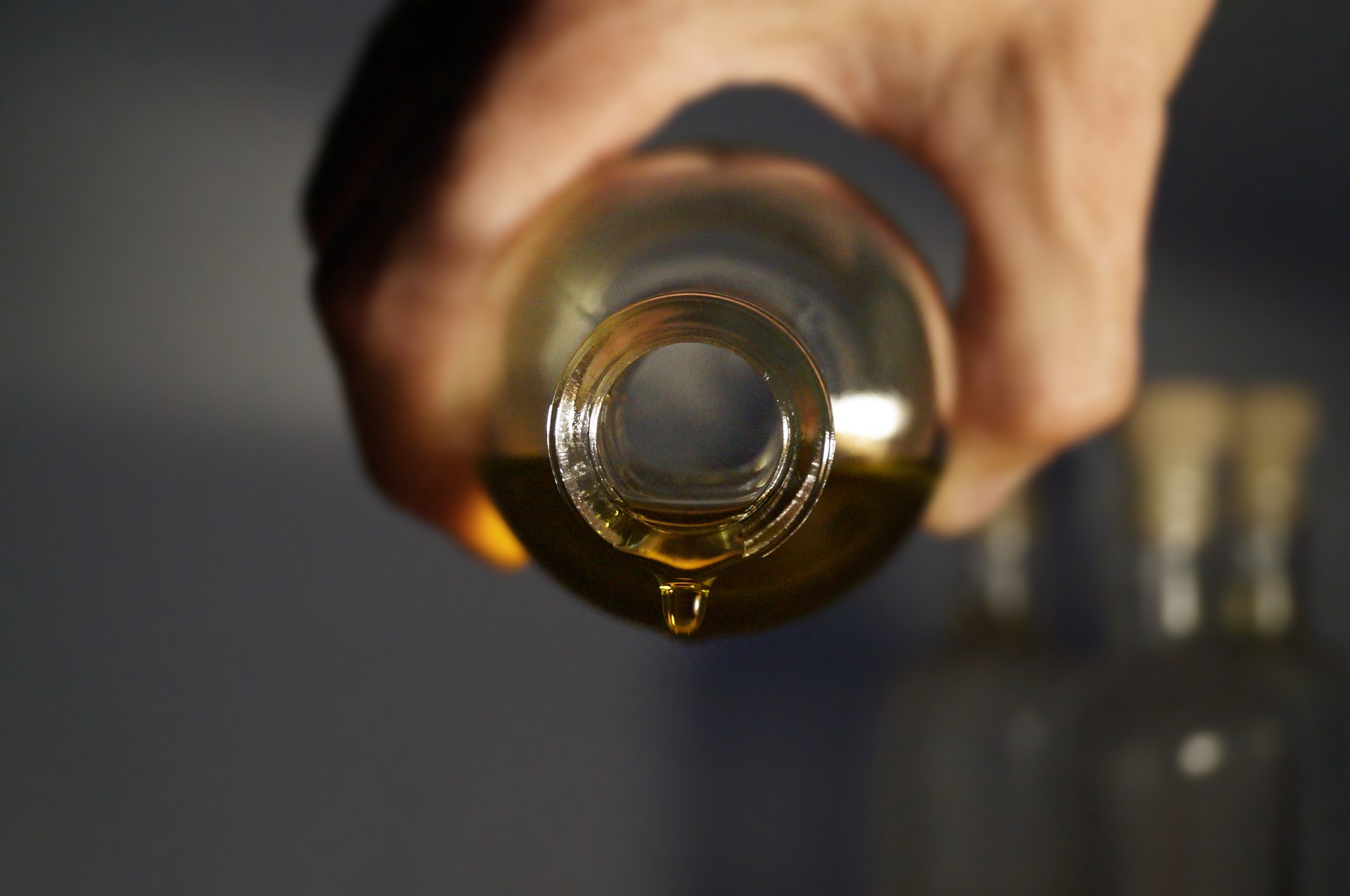 a hand pouring a oil from a glass bottle