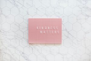 pink pin board with the words kindness matters in white on a marble background