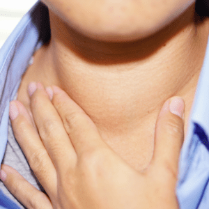 a close up of someone with their hand to their neck wearing a blue shirt
