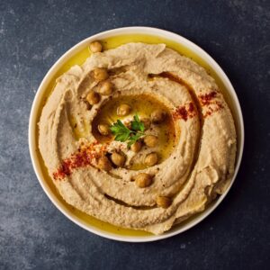 Plan view of a ramekin full of hummus sprinkled with paprika