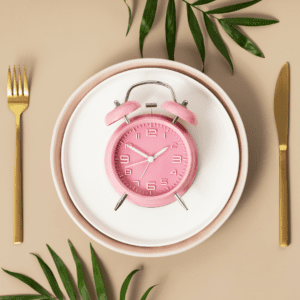plate with a pink alarm clock, gold knife and fork with palm leaves