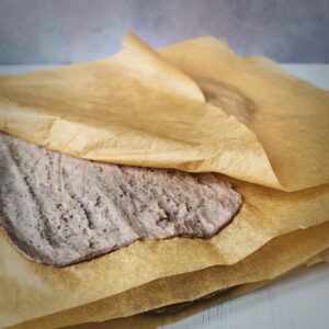 A stack of low carb bread wraps in baking paper with a grey background
